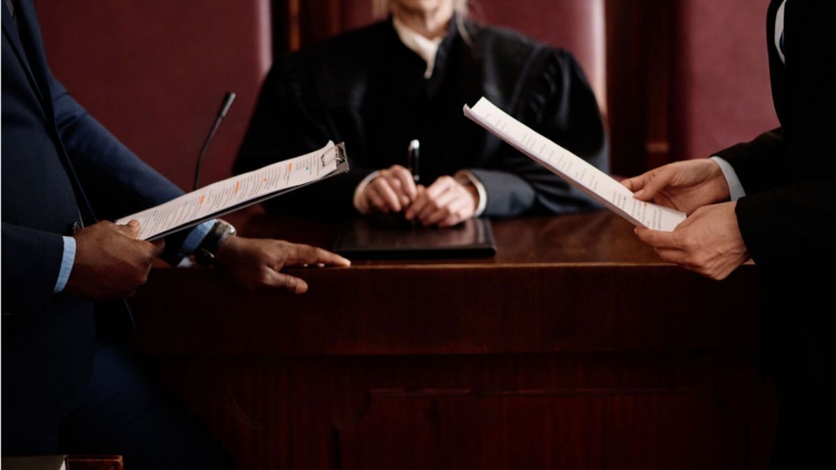 Two individuals in suits engage in discussion before a judge, highlighting the nature of offenses in criminal and civil law.