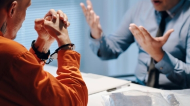 Two men sit at a table while discussing the legal aspects of kidnapping.