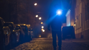 Investigator with a flashlight searching a street at night