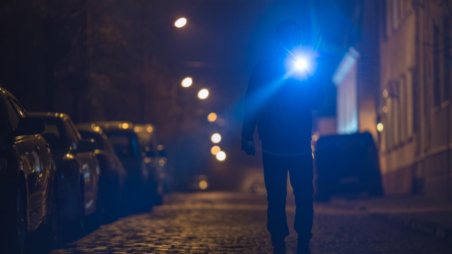 Investigator with a flashlight searching a street at night
