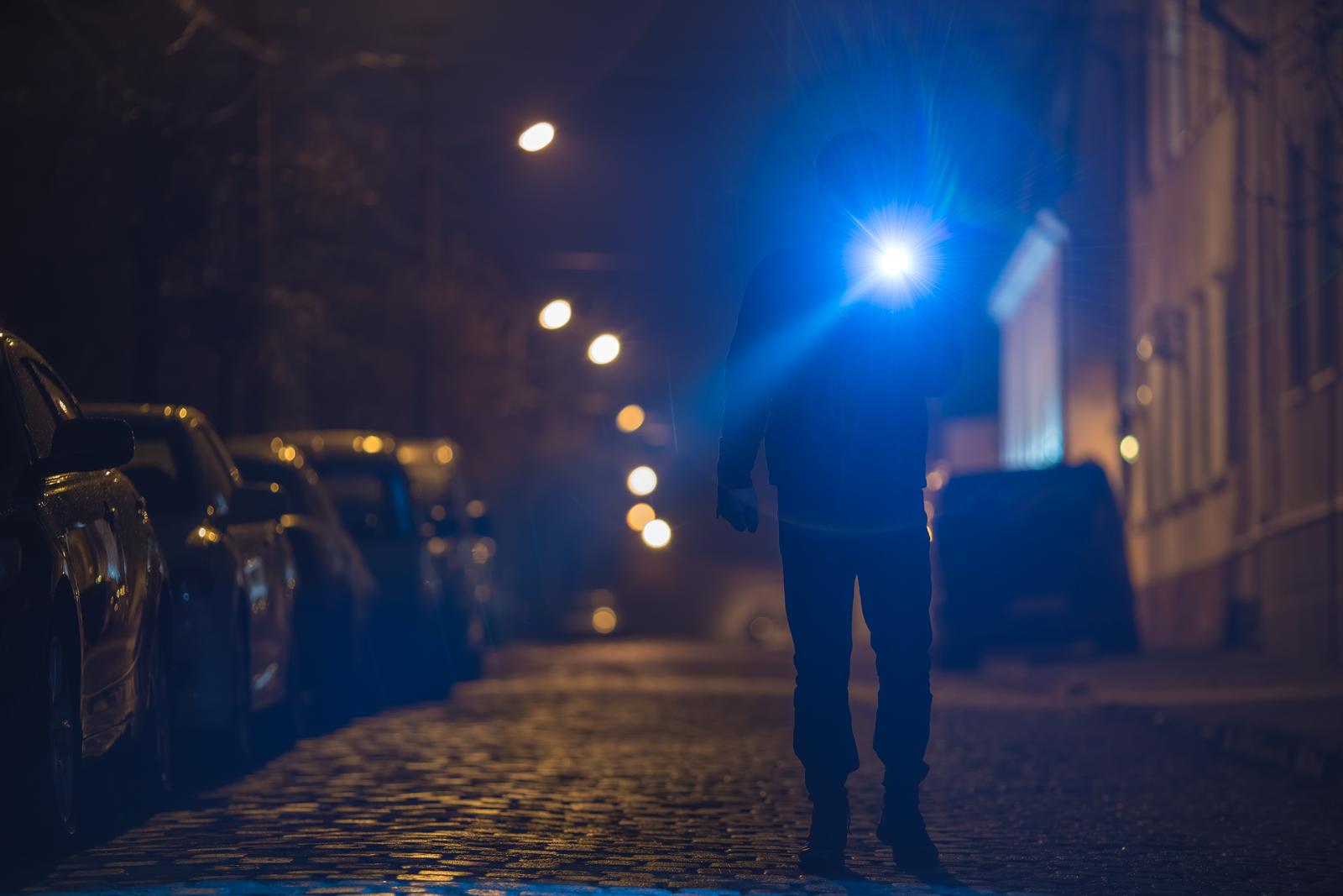 Investigator with a flashlight searching a street at night